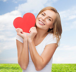 Image showing smiling woman in white t-shirt holding red heart