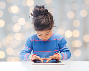 Image showing little girl with tablet pc over lights background