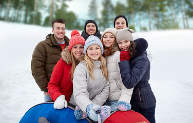 Image showing smiling friends with snow tubes and selfie stick