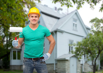 Image showing smiling manual worker in helmet with pait roller