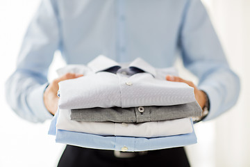 Image showing close up of businessman holding folded shirts