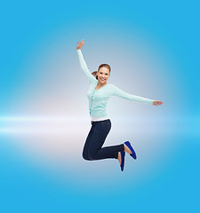 Image showing smiling young woman jumping in air