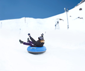 Image showing happy young man sliding down on snow tube