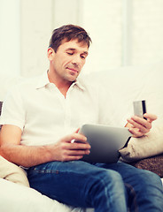 Image showing man with tablet pc and credit card at home