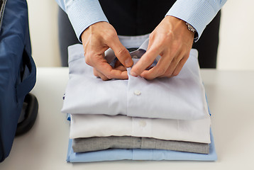 Image showing businessman packing clothes into travel bag