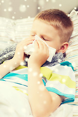 Image showing ill boy blowing nose with tissue at home