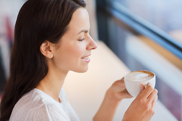 Image showing smiling young woman drinking coffee at cafe