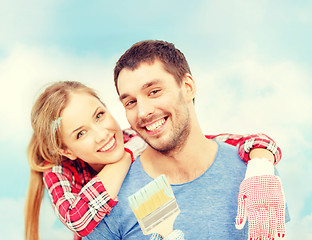 Image showing smiling couple covered with paint with paint brush