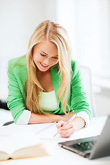 Image showing smiling student girl writing in notebook