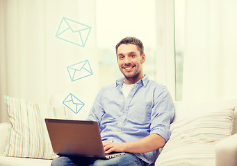 Image showing smiling man working with laptop at home