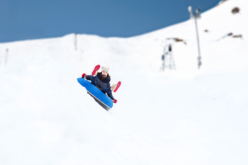 Image showing happy teenage girl sliding down on snow tube