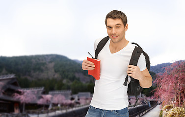 Image showing happy young man with backpack and book travelling