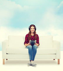 Image showing girl sitting on sofa with headphones and tablet pc