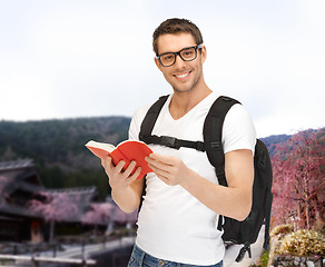 Image showing happy young man with backpack and book travelling