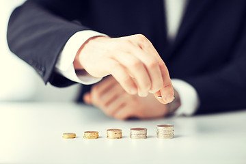 Image showing man putting stack of coins into one row