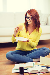 Image showing student eating hamburger and doing homework