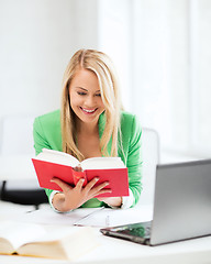 Image showing smiling student girl reading book in college