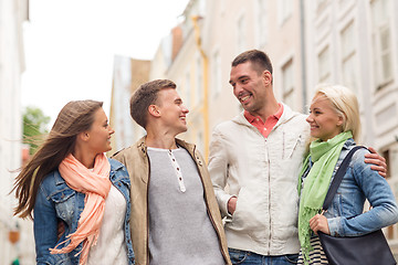 Image showing group of smiling friends walking in the city