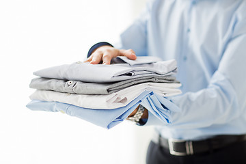 Image showing close up of businessman holding folded shirts