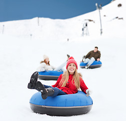 Image showing group of happy friends sliding down on snow tubes