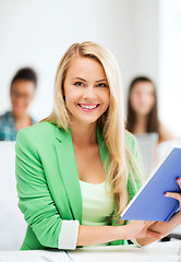 Image showing smiling young girl reading book at school