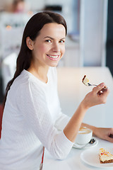 Image showing smiling young woman with cake and coffee at cafe