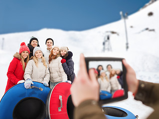 Image showing smiling friends with snow tubes and tablet pc