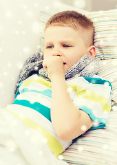 Image showing ill boy with scarf lying in bed and coughing