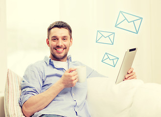 Image showing smiling man working with tablet pc at home