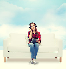 Image showing girl sitting on sofa with headphones and tablet pc