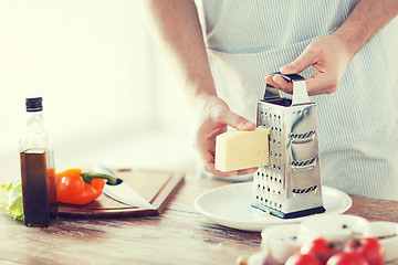 Image showing close up of male hands grating cheese