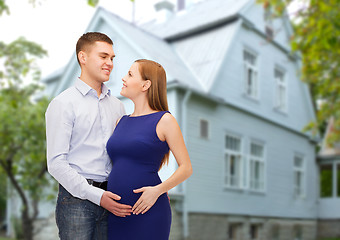 Image showing happy young family expecting child over house