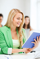 Image showing smiling young girl reading book at school