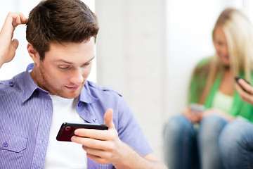 Image showing student looking at phone and writing something