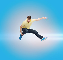 Image showing smiling young man jumping in air