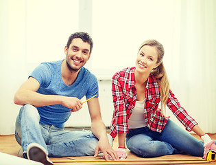Image showing smiling couple measuring wood flooring