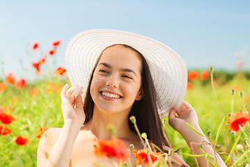 Image showing smiling young woman in straw hat on poppy field