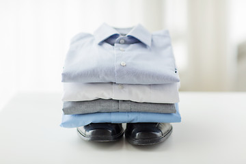 Image showing close up of folded male shirts and shoes on table