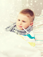 Image showing ill boy with thermometer lying in bed at home