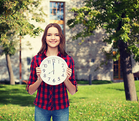 Image showing young woman in casual clothes with wall clock