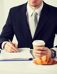 Image showing businessman with coffee writing something