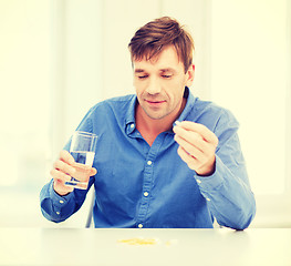 Image showing ill man taking his pills at home