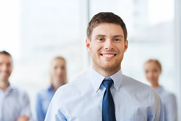 Image showing smiling businessman with colleagues in office