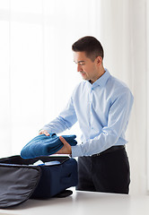 Image showing businessman packing clothes into travel bag