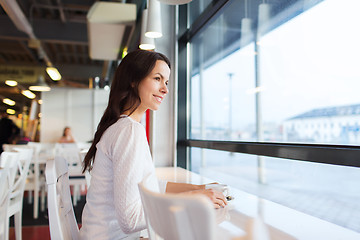 Image showing smiling young woman drinking coffee at cafe