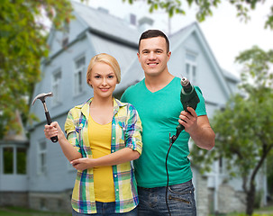 Image showing smiling couple with hammer and drill over house