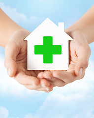 Image showing hands holding paper house with green cross