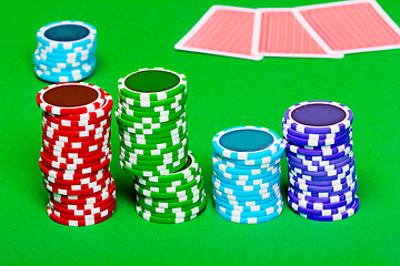 Image showing chips on the background of green the table. Cards in the backgro