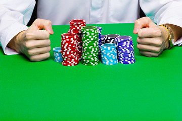 Image showing Man with a bunch of chips. Green table
