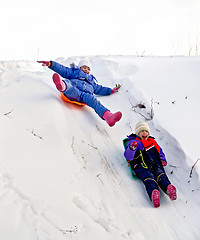 Image showing Two girls on sled through the snow to slide
